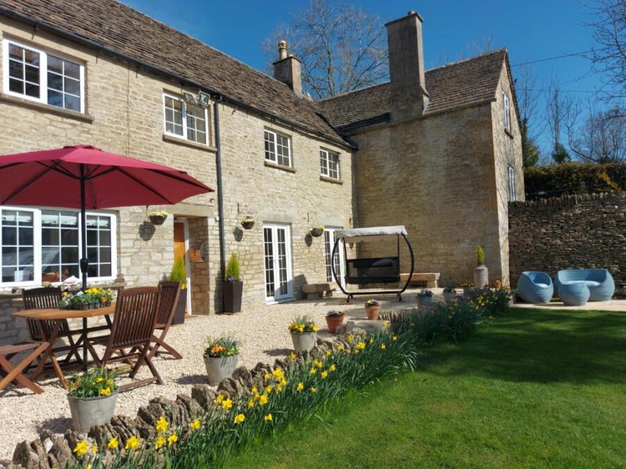Thames Head Wharf's historic Cotswold cottage, showcasing a patio equipped with a table and chairs for relaxation.