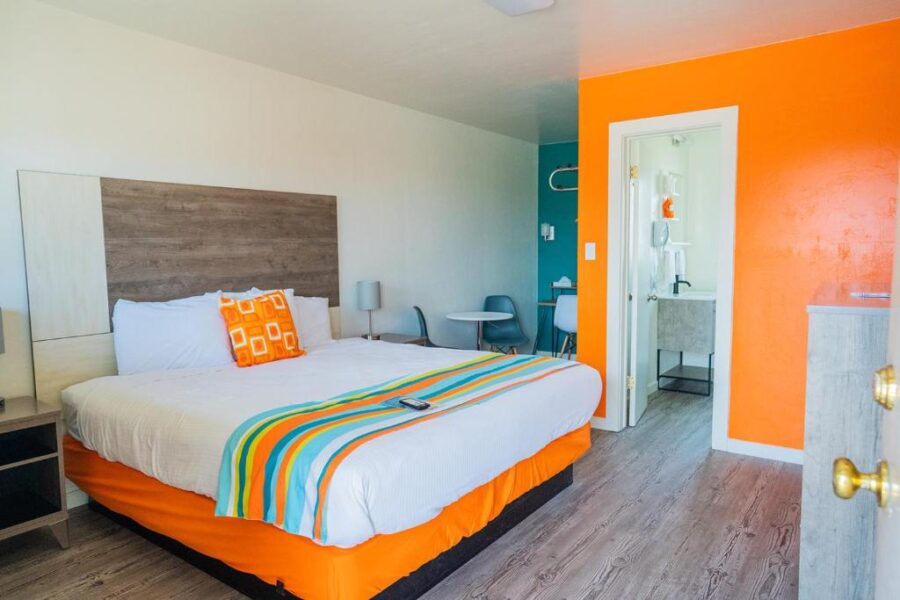 Bright hotel room with orange walls and a comfortable bed at the Atomic Blue Motor-Inn.