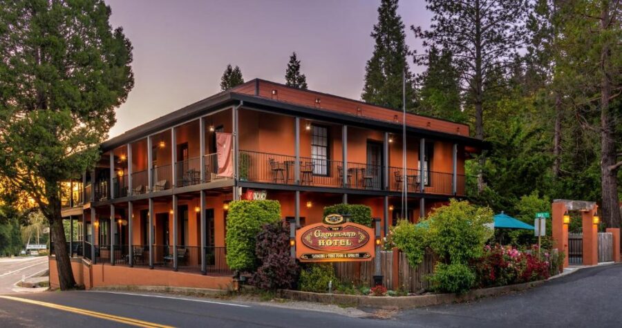 The Groveland Hotel, a charming inn atop a hill, surrounded by lush trees and scenic views of Yosemite.