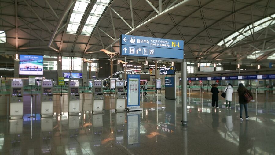 Crowds of people navigate the spacious terminal of Incheon International Airport, showcasing its busy atmosphere.