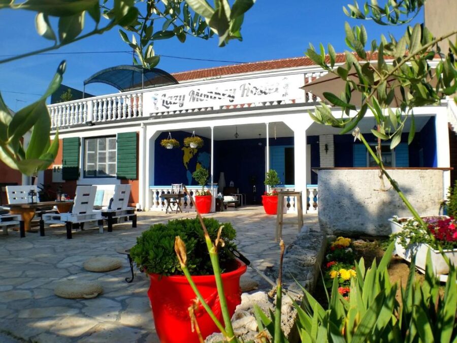 The Lazy Monkey Hostel & Apartments, showcasing a house with a patio and a lush garden in a serene environment.