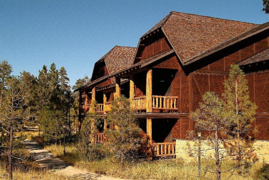 The Lodge at Bryce Canyon, a spacious wooden building featuring a porch and balcony, set against a picturesque backdrop.
