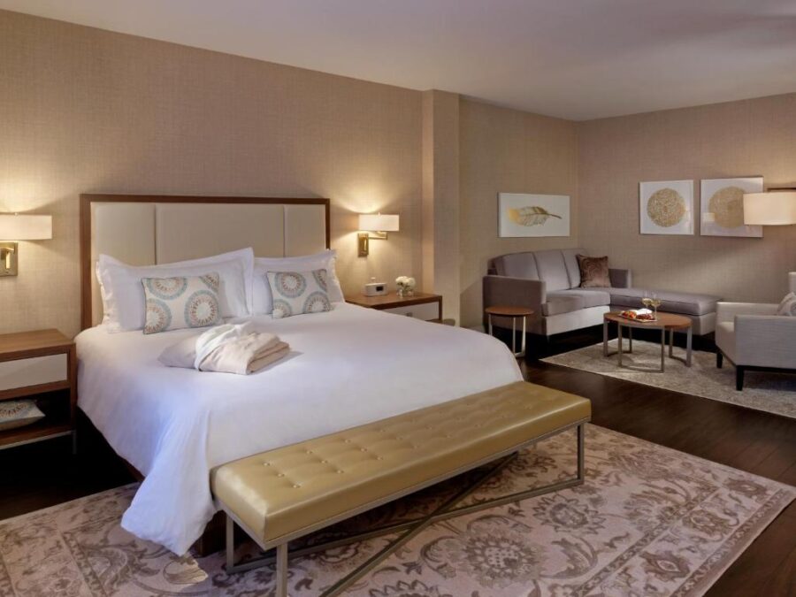 The Lord Nelson Hotel & Suites room showcasing a king bed, a cozy couch, and a chair for relaxation.