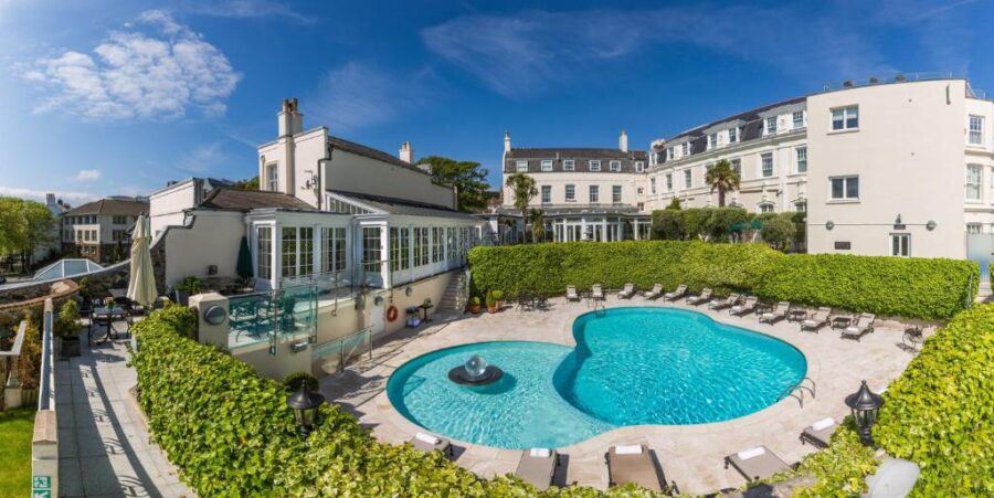 The hotel pool at The Old Government House Hotel & Spa in Guernsey, surrounded by lush green hedges.
