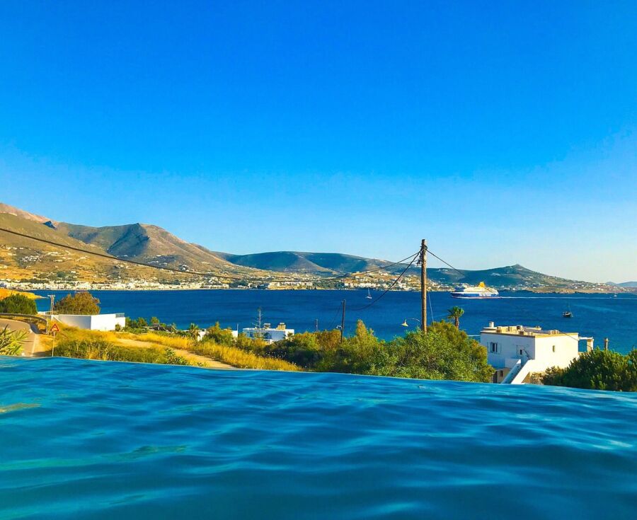 Scenic view from a villa pool in Parikia, Greece, showcasing the sparkling sea and surrounding landscape.