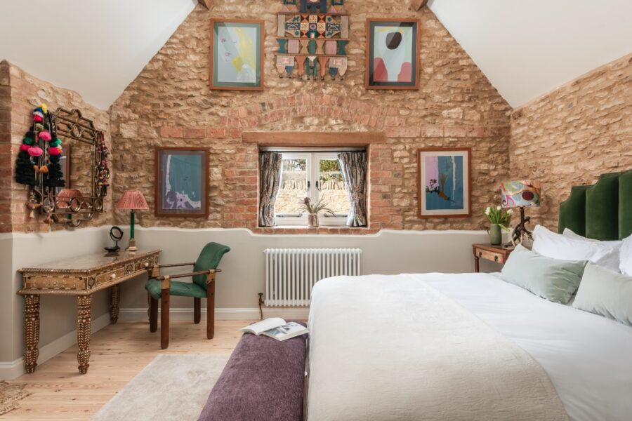 Interior of a bedroom with a bed, desk, and window, situated in The Ruby Barn, Chipping Norton, Cotswolds.