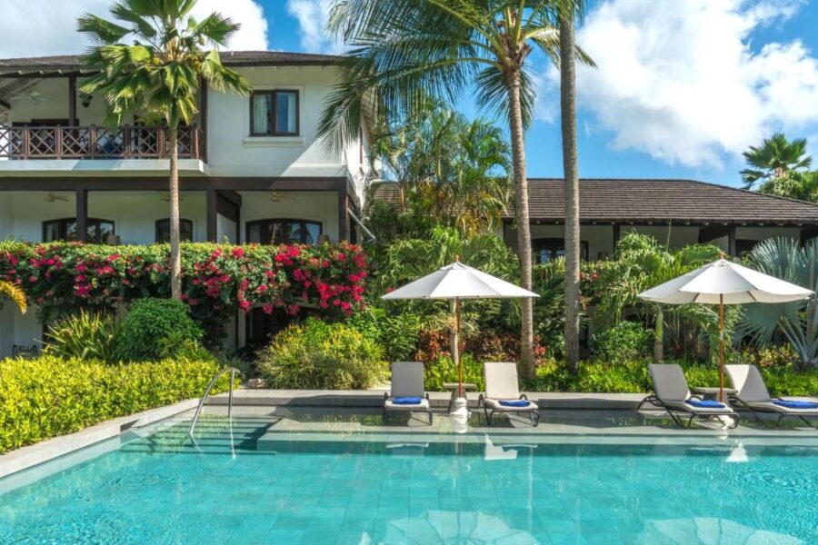 Picturesque villa at The Sandpiper beach club in Barbados, surrounded by palm trees and overlooking the beach.