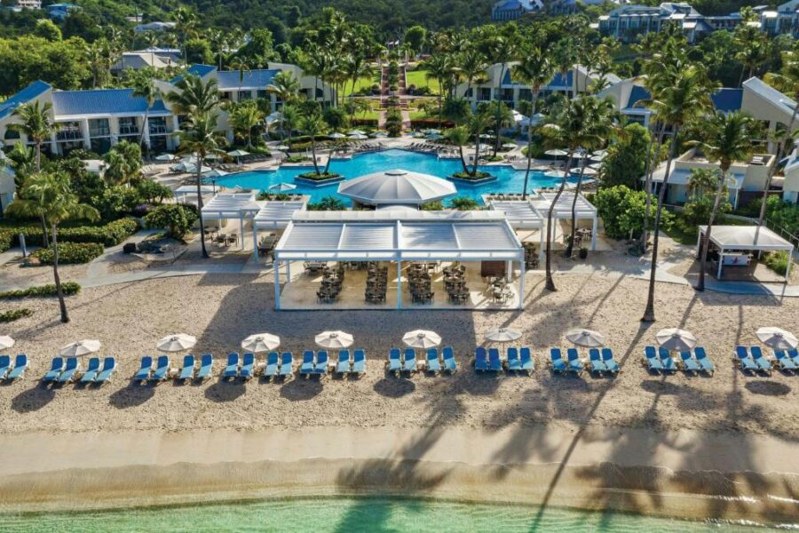 Pool area at The Westin St. John Resort Villas, featuring clear water surrounded by palm trees and lounge chairs.
