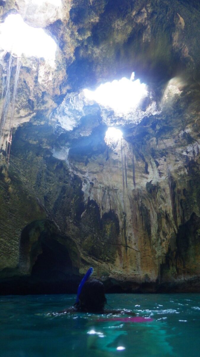 People swimming in the blue waters of Thunderball Grotto, a stunning cave in the Bahamas.