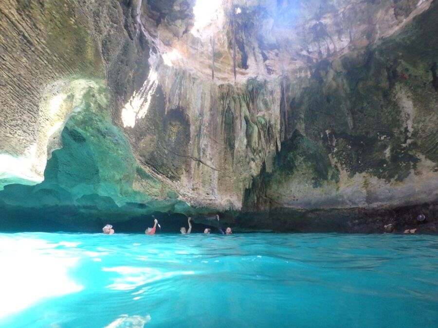 People swimming in the blue waters of Thunderball Grotto, a stunning cave in the Bahamas.