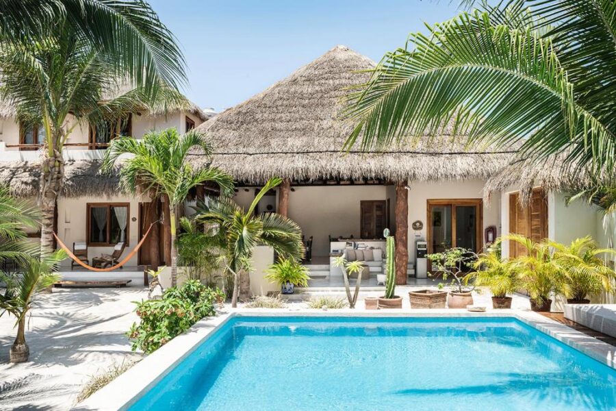 Inviting pool area of Tierra del Mar Hotel, framed by palm trees and thatched roofs, located on Isla Hoblox.

