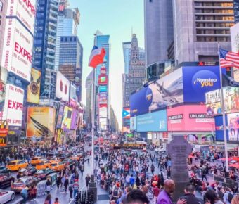 Times Square NYC bustling with vibrant crowds, colorful billboards, yellow taxis, and diverse architecture.