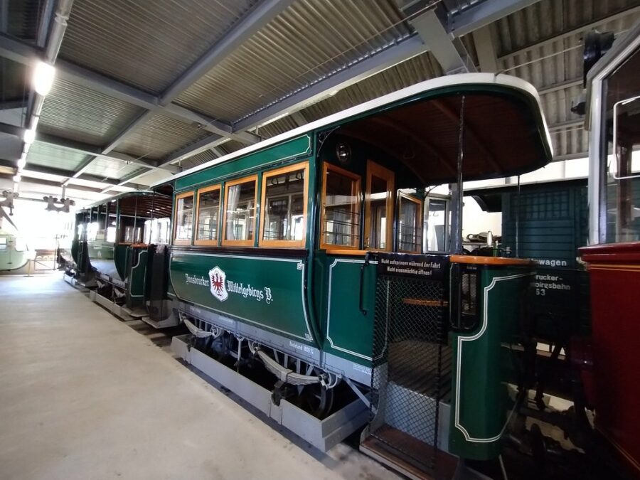 Green and white train parked inside a building at Tiroler MuseumsBahnen in Austria.
