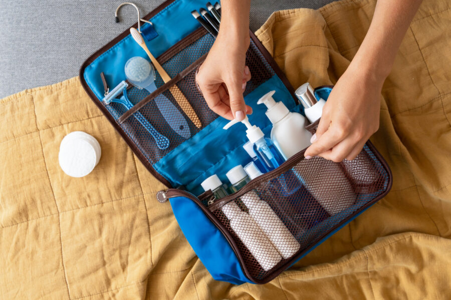 Organized blue toiletry bag with grooming essentials on a yellow background for travel and self-care.