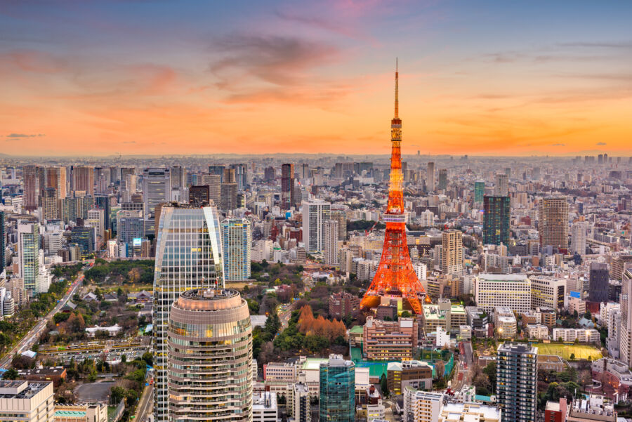 Tokyo cityscape at dusk, featuring illuminated buildings and the iconic Tokyo Tower against a twilight sky