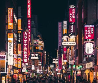Tokyo nightlife: vibrant streets with neon signs, lively crowds, Japanese cuisine, and cultural blend.