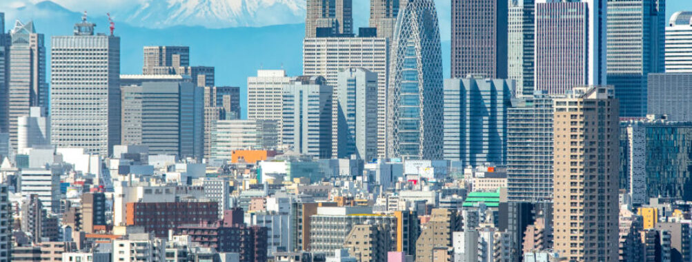 Cityscape of Shinjuku, Tokyo, with modern buildings in the foreground and Mt. Fuji rising majestically in the background.