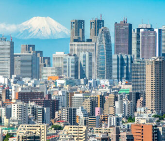 Cityscape of Shinjuku, Tokyo, with modern buildings in the foreground and Mt. Fuji rising majestically in the background.