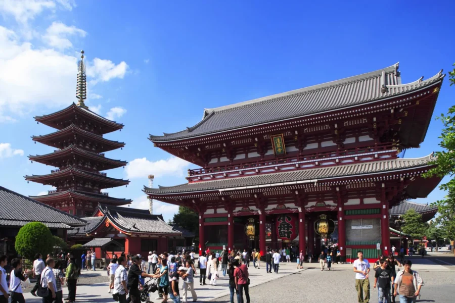 Tokyo Sensoji Temple pagoda and Thunder Gate with tourists under blue sky in Asakusa, Japan.
