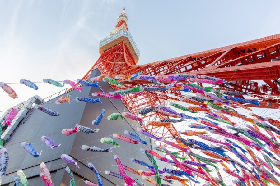 Tokyo Tower with vibrant koinobori streamers celebrating Childrens Day under a clear blue sky.