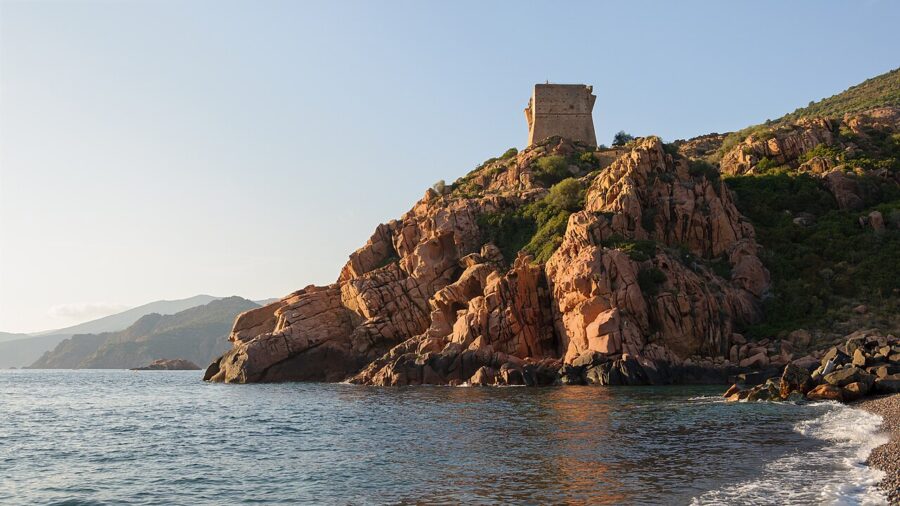 Torra di Portu, a tower perched on a rocky cliff, offers a stunning view of the ocean in Corsica, France.