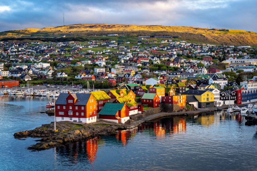 Torshavn at sunrise, with Scandinavian buildings illuminated by soft golden light, creating a serene urban landscape.