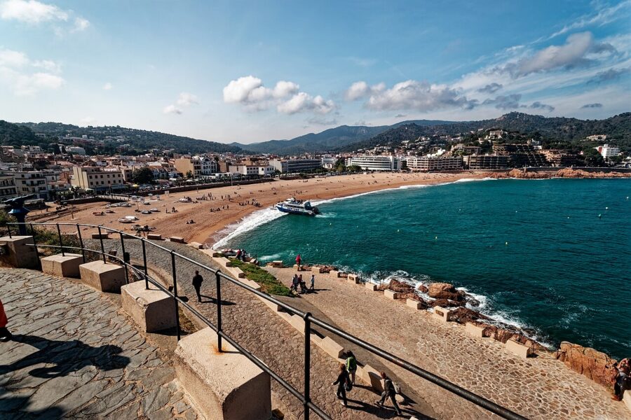 Several boats are moored in a picturesque harbor on the Costa Brava, Spain, reflecting the vibrant coastal scenery