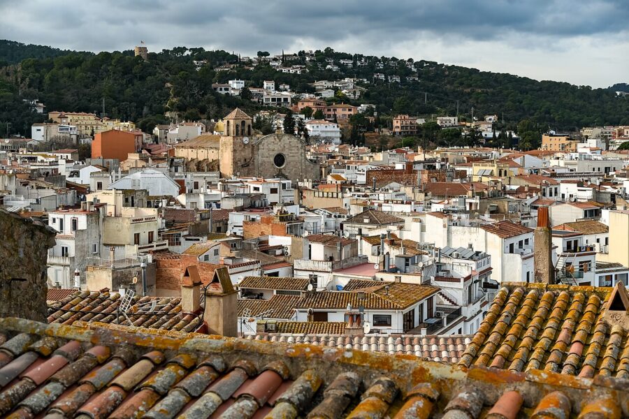 Panoramic view of Tossa de Mar, showcasing numerous buildings against a clear sky.