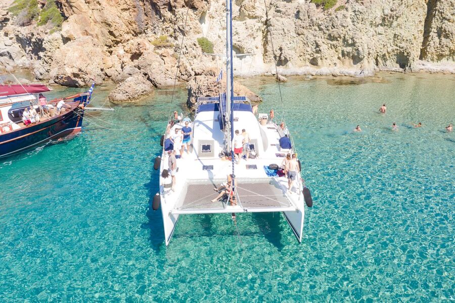 Catamaran sailing in the clear blue waters near Kleftiko, showcasing the beauty of the island's coastline.
