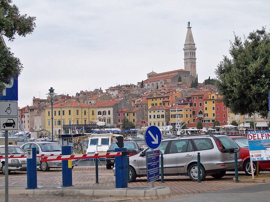 Cars parked in a lot with a clock tower visible, set on a street in the charming town of Rovinj, Croatia.