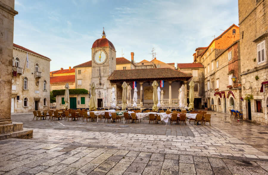 Charming Mediterranean town square with historic architecture and a central clock tower.