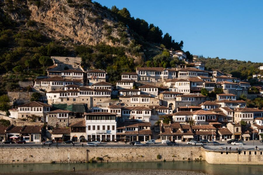 Charming hillside Albanian village with stone houses, terracotta roofs, and serene waterfront.