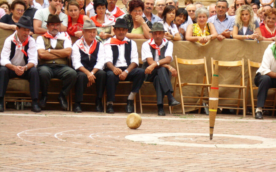 Traditional outdoor bowling game at Fiera del Cacio cheese festival with engaged crowd.