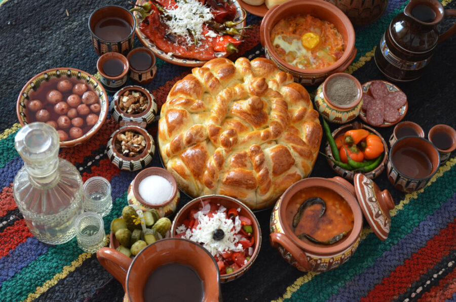 Traditional Balkan feast with artisanal bread, vibrant salads, and savory dishes on woven textile.