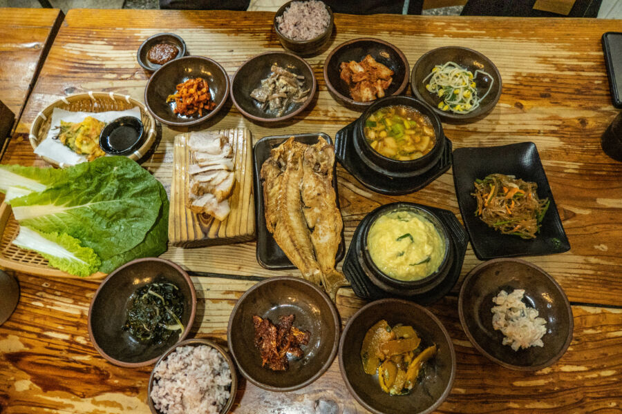 Traditional Jeju Island feast featuring fish, black pork, and various banchan side dishes in Seogwipo, Jeju, South Korea