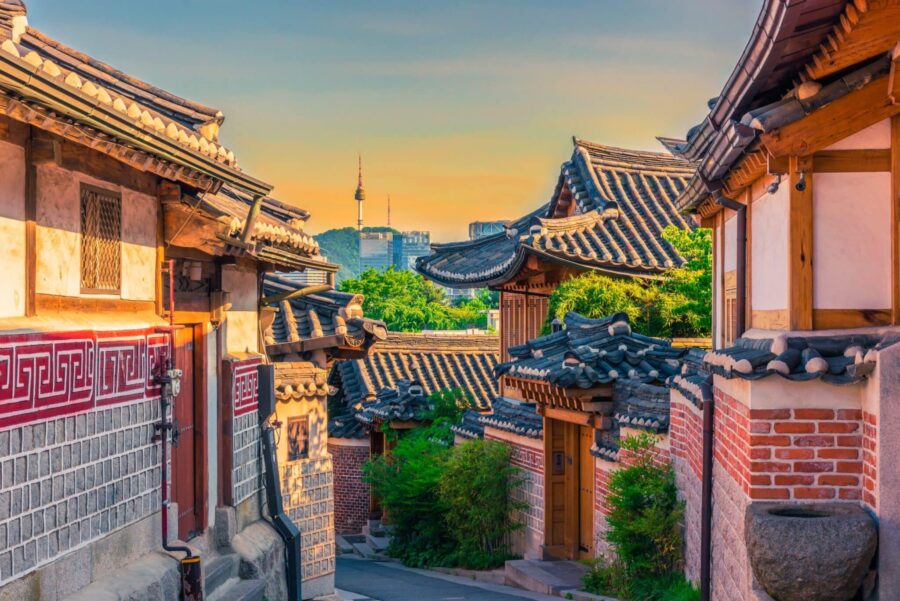 Traditional Korean hanoks with Seoul Tower at sunset; blending history and modernity.