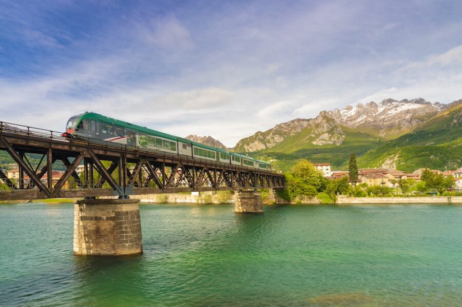 Train on railway bridge over Adda River, with Resegone Mountain in background, Lecco, Lombardy.