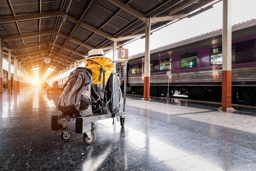 Train station platform with a purple train and travel gear, evoking adventure and nostalgia.