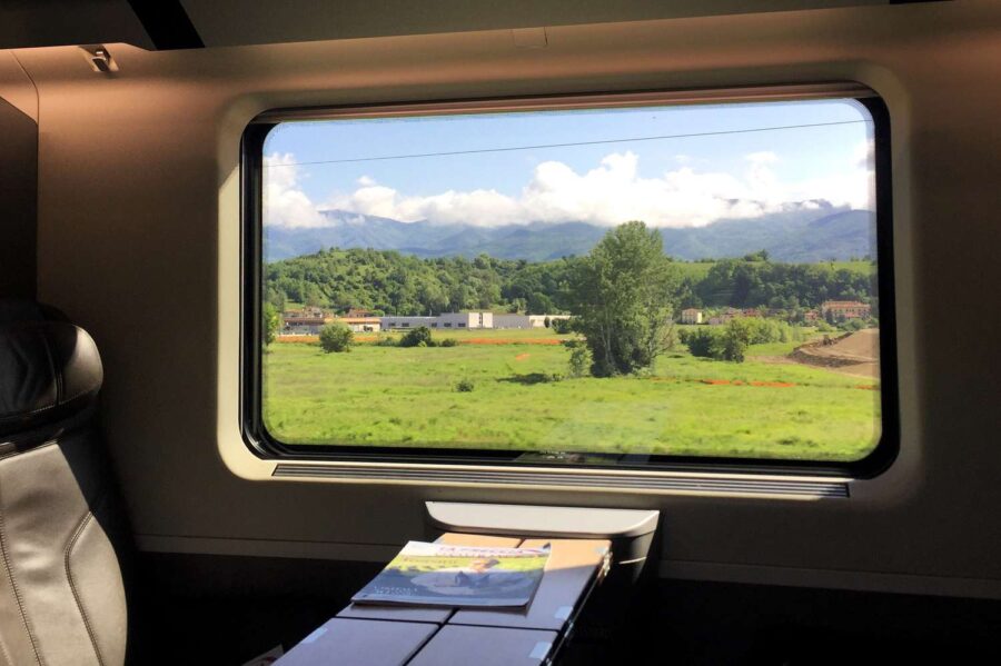 Luxury train interior with scenic view of green hills and mountains through the window.