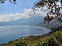A serene lake with mountains, trees, and blue sky reflecting picturesque nature.