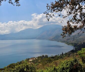 A serene lake with mountains, trees, and blue sky reflecting picturesque nature.