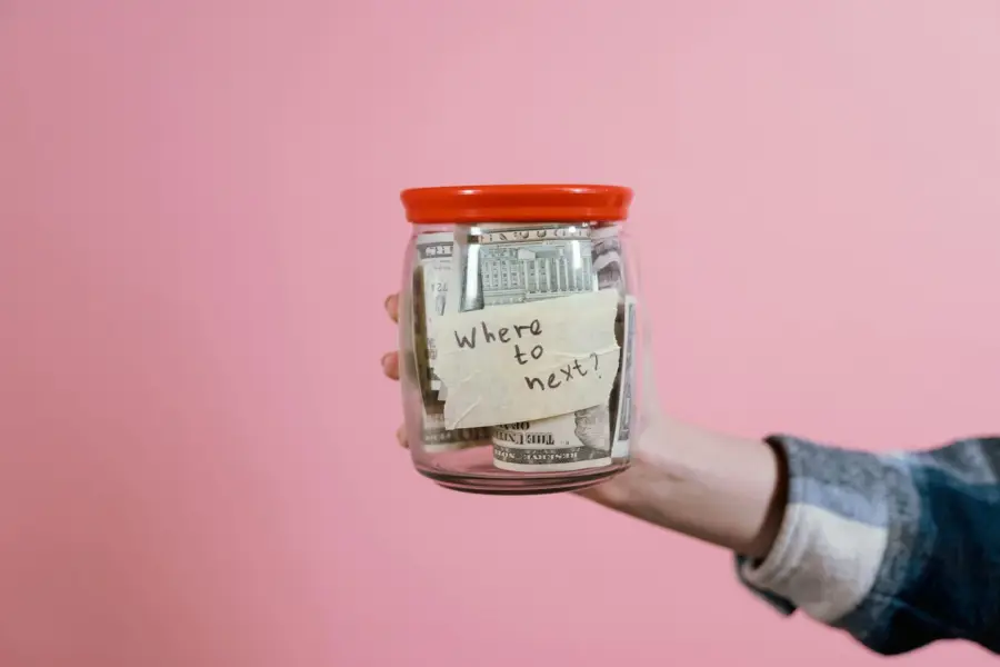 A person with a jar containing travel savibgs