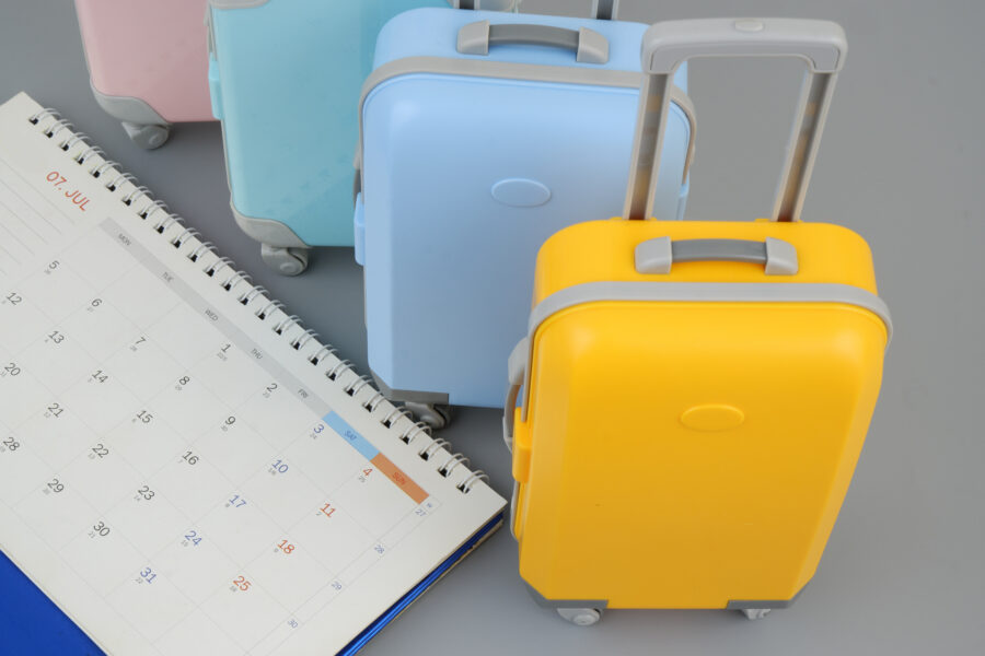 Various suitcases arranged next to a calendar, representing the concept of planning trips and vacations.