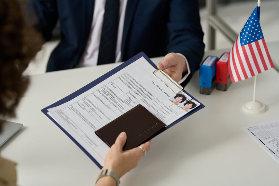 Close-up of a woman submitting her visa application and travel documents to an immigration officer in the US