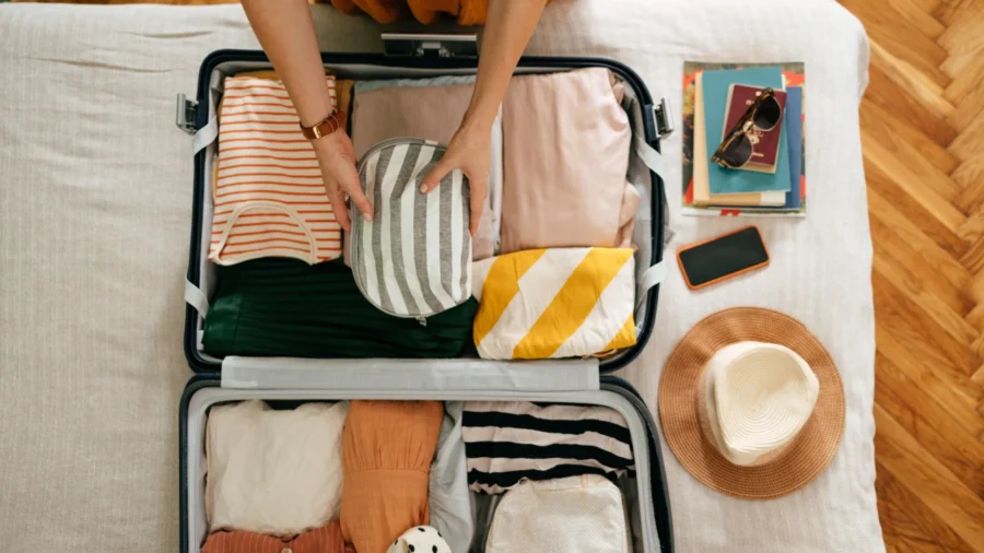 Organized suitcase packing with clothing, accessories, books, and hats for a stylish travel.