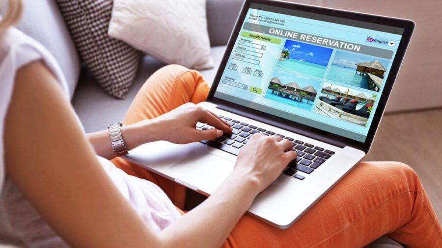 Person booking tropical vacation online from home on a laptop.