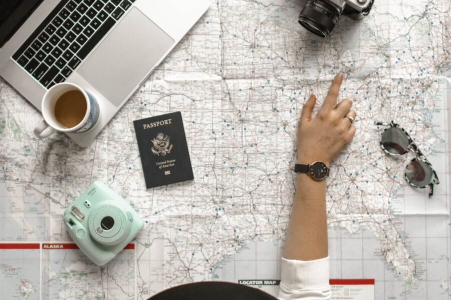 Travel essentials: map, laptop, passport, camera, and coffee evoke adventure and exploration.