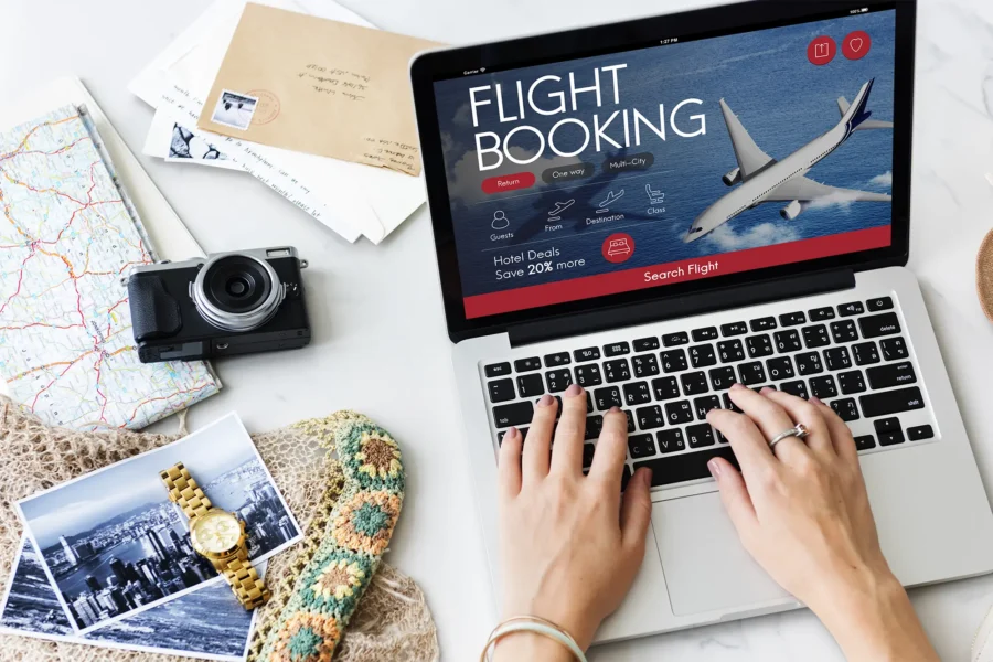 Travel planning workspace with laptop, map, camera, and cozy items for adventure preparation.
