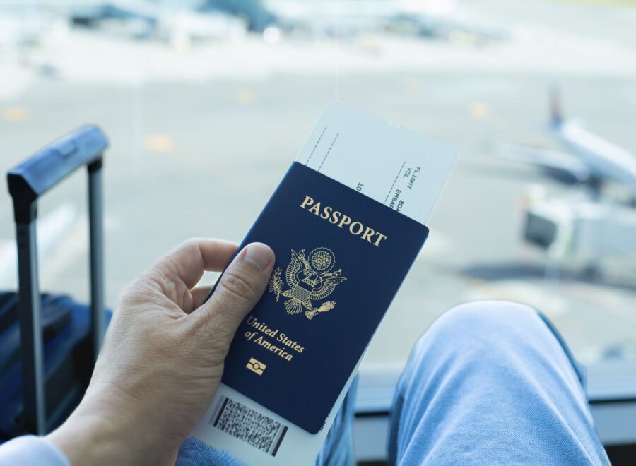 Traveler holding a blue passport in a bustling airport, ready for international adventure.