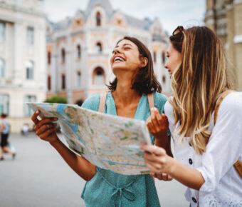 Two female travelers consult a map while exploring the city, seeking directions to their next destination